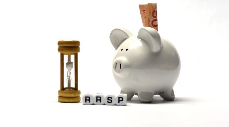 The Letter dices RRSP next to a white ceramic piggybank and a wooden hourglass. A fifty dollar banknote is inserted into the piggybank's slot.