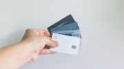 A person's hand holding four credit cards spread out in a fan