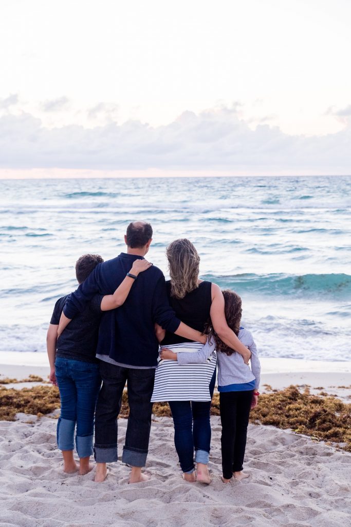 Family of four standing at a beach looking out over the ocean